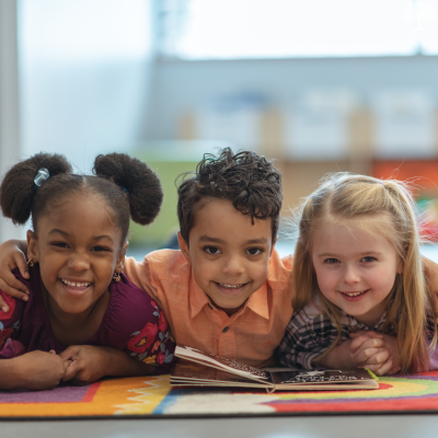 Group of kids smiling while reading a book together.
